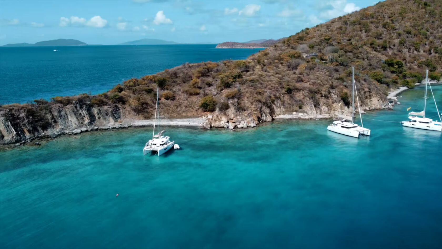 A group of sailboats docked on a rocky island.