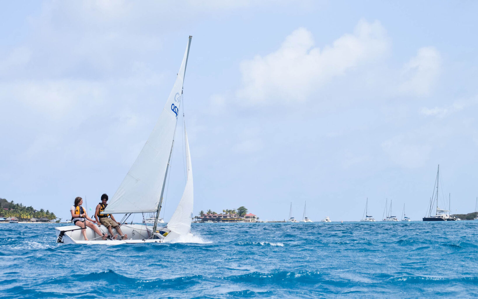 Two people on a sailboat in the ocean.