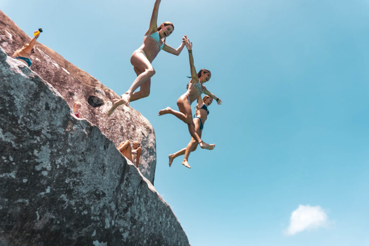 A group of people jumping off a rock.