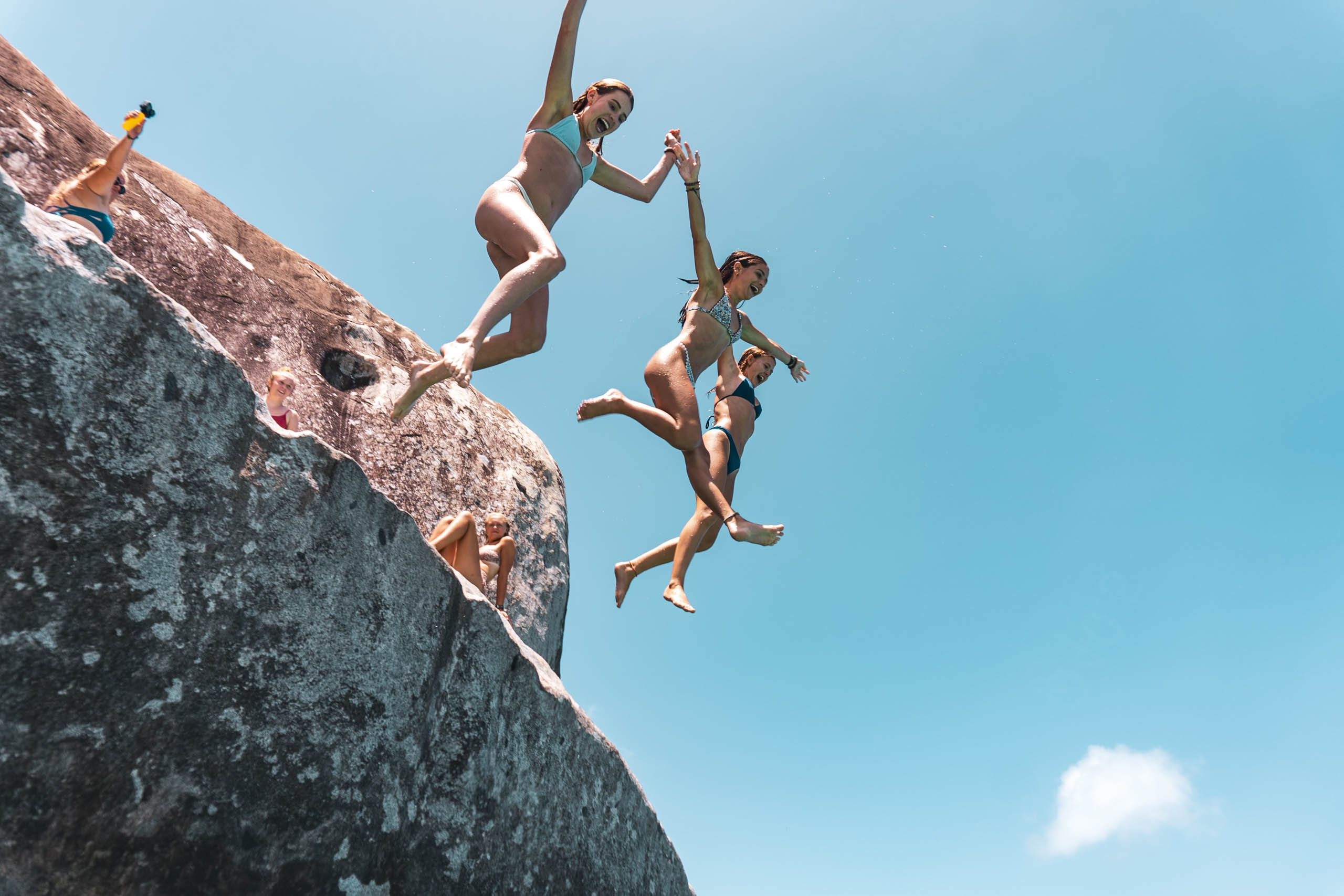 A group of people jumping off a rock.