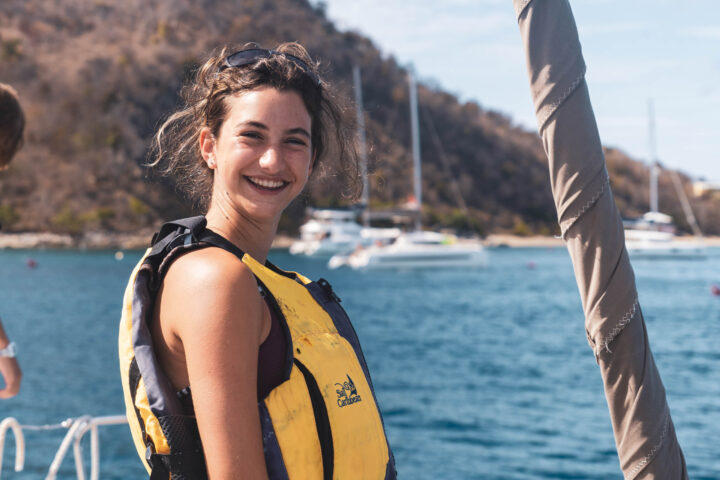 A woman in a yellow life jacket on a boat.