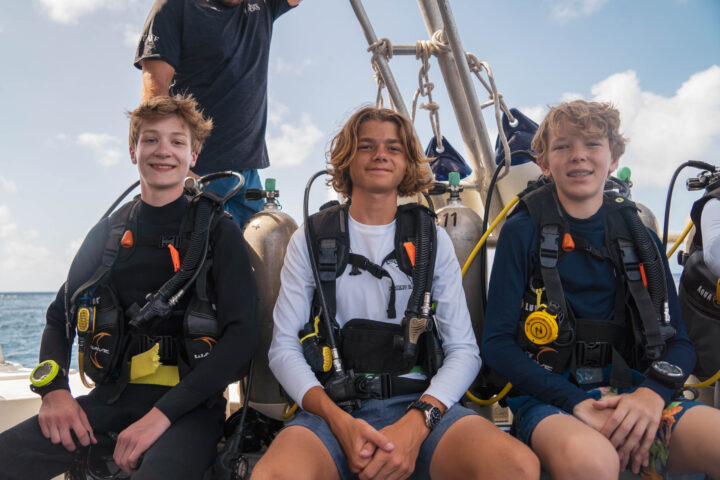 Divers in dive gear on a boat.