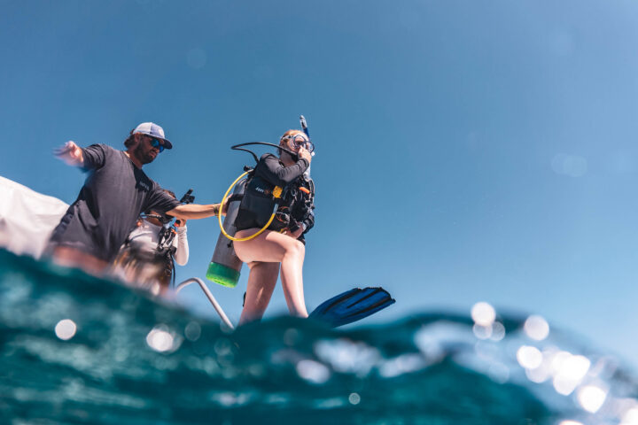 Camper jumping into the water with dive gear on.