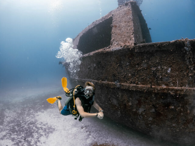 Camper diving near a sunken boat.
