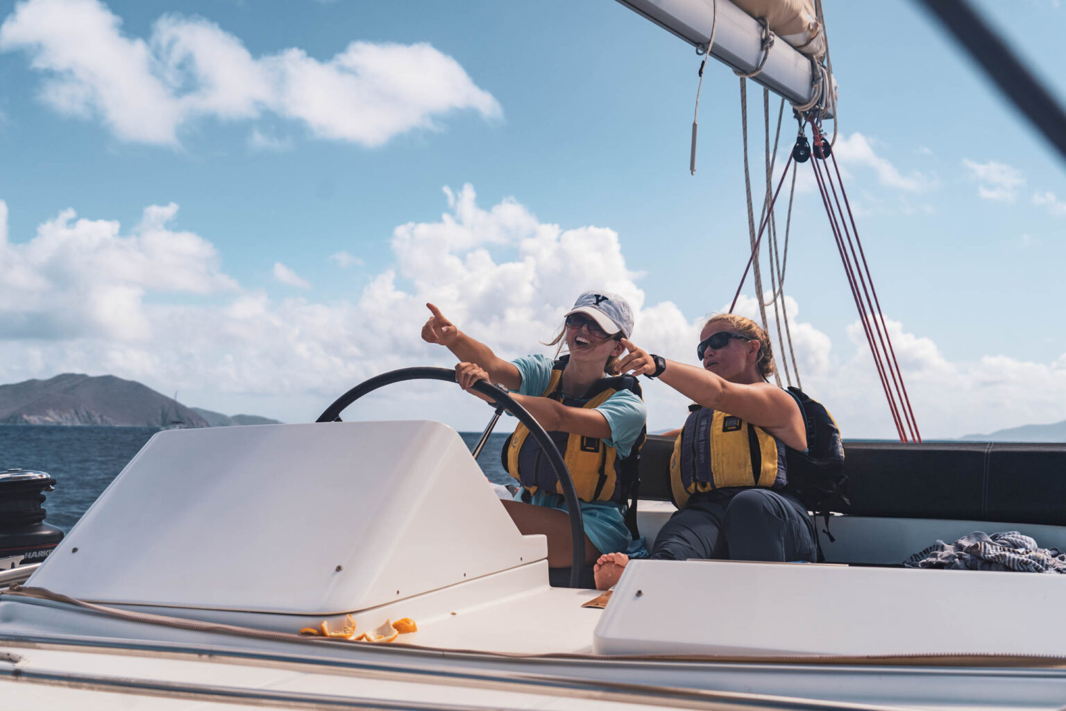 Two women are driving a sailboat in the ocean.