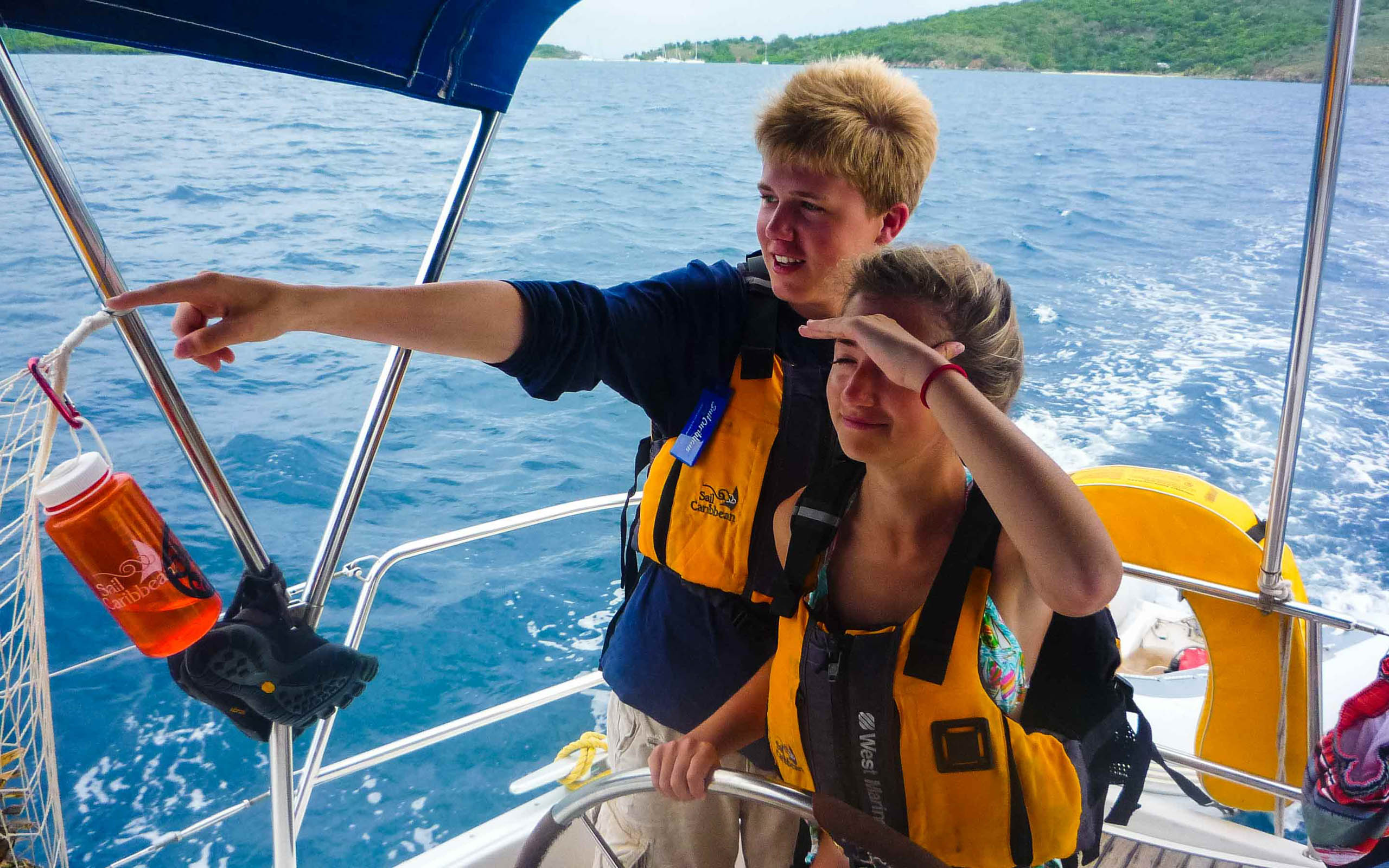 Two people on a boat pointing at something in the water.