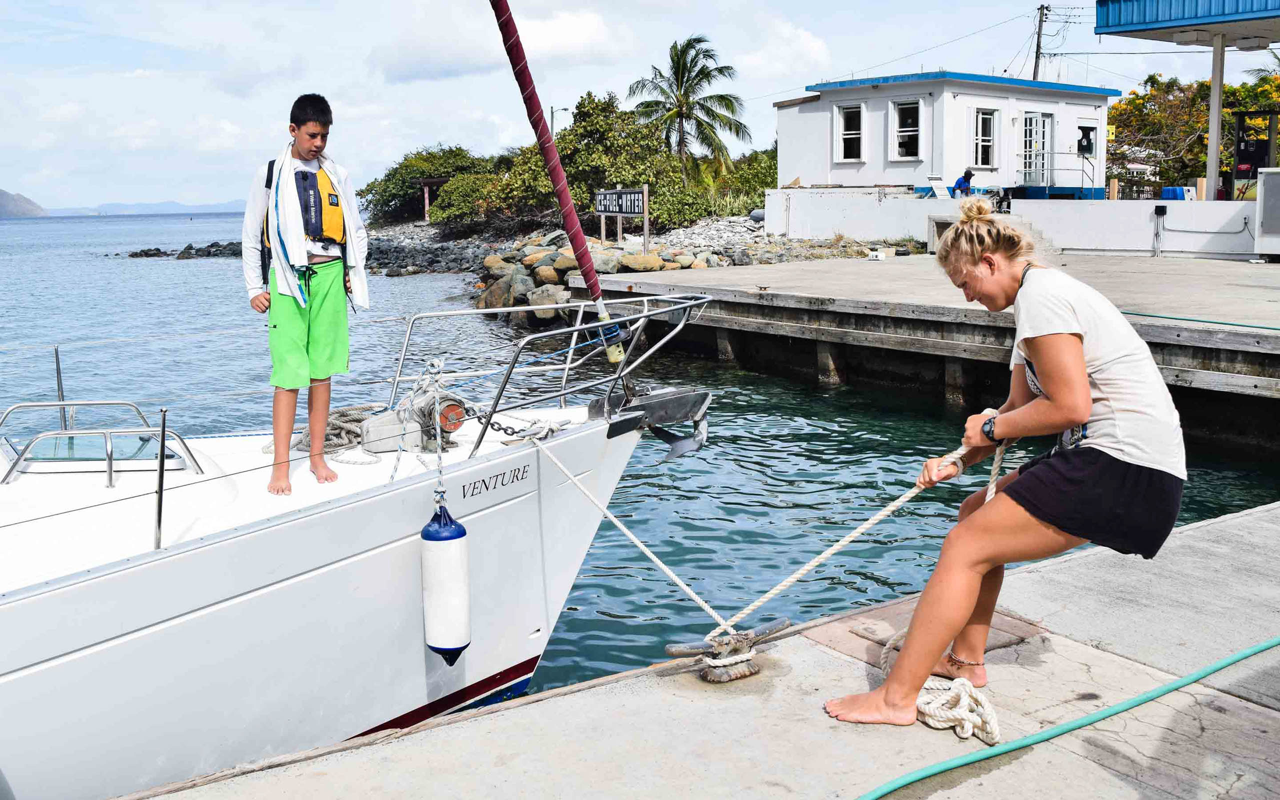 A man and a woman standing next to a white sailboat.
