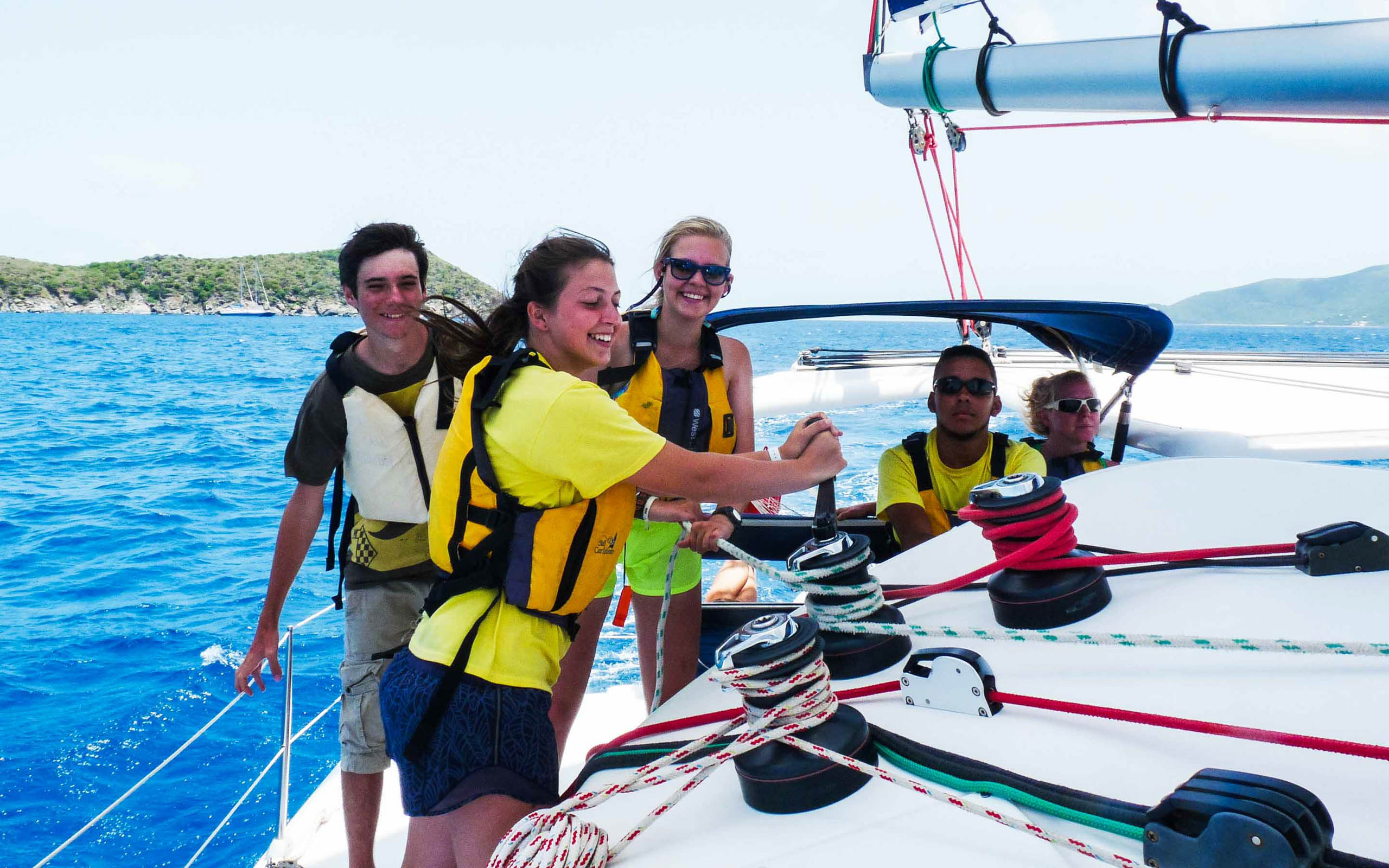 A group of people on a sailboat in the ocean.