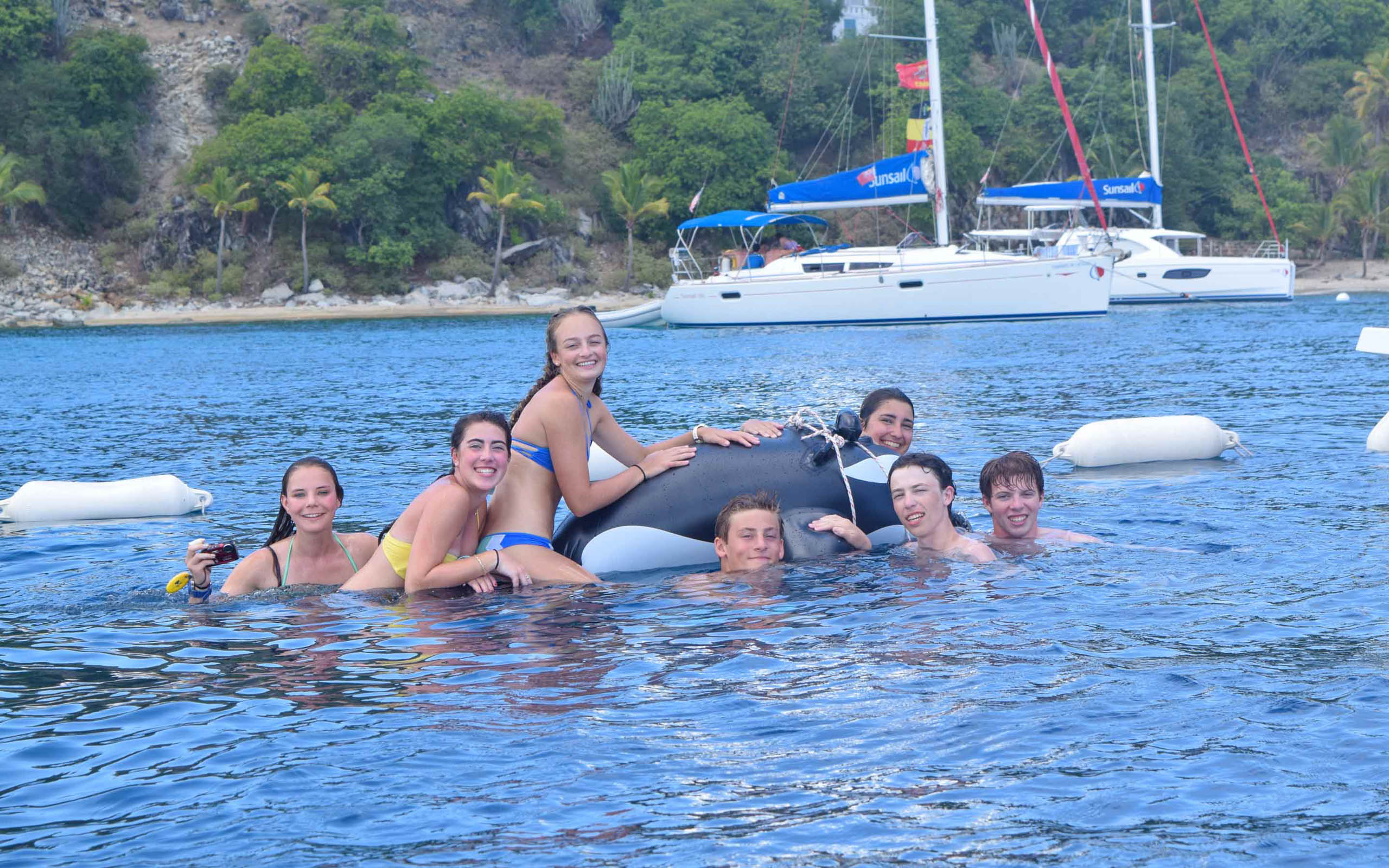 A group of people posing in the water with an orca.