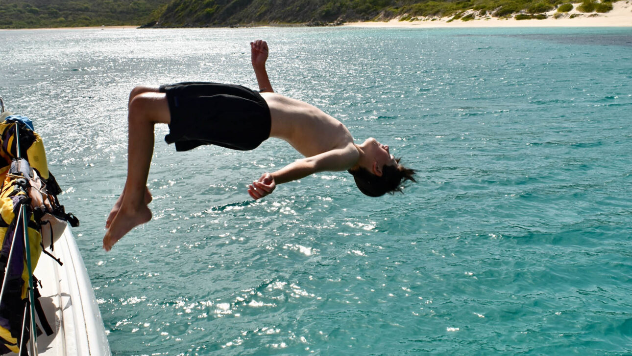 Camper back flipping off the boat into the ocean.