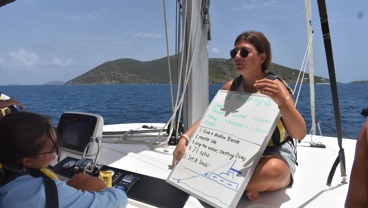 A woman holding a white board on a boat.