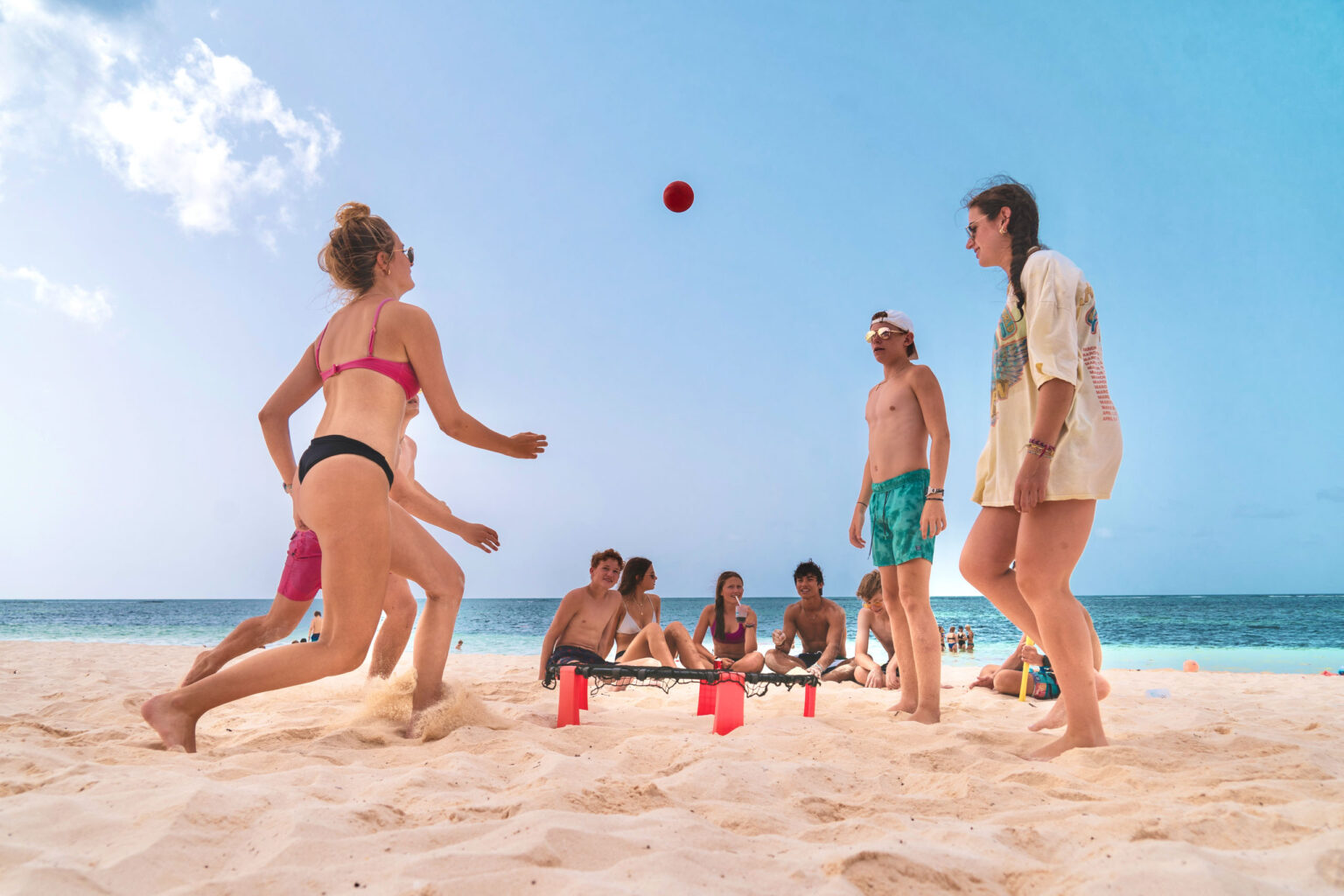 A group of people playing frisbee on the beach.